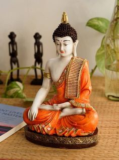 a buddha statue sitting on top of a wooden table