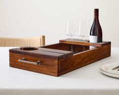 a wooden tray with two wine glasses and a bottle sitting on top of a table