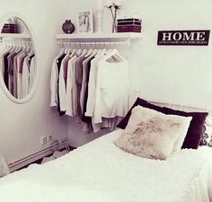 a bedroom with a bed, mirror and clothes on hangers in it's corner