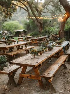 an outdoor picnic area with wooden benches and tables set up for dinner under the trees