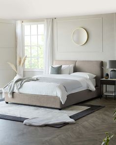 a white bed sitting in a bedroom next to a window