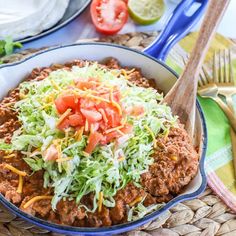 a bowl filled with taco meat and lettuce next to a plate of tomatoes