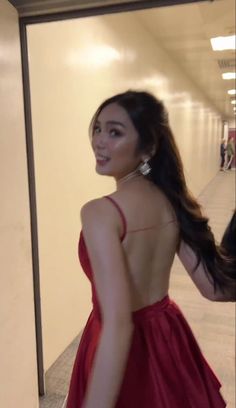 a woman in a red dress walking down a hallway