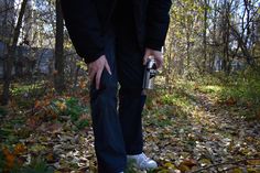 a person standing in the woods with their camera on his hip and holding onto some leaves