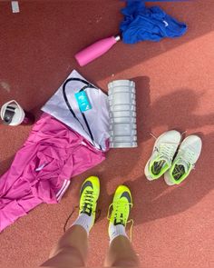 a person's feet are shown next to sports equipment and water bottles on the ground