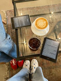 a person sitting at a table with two tablet computers and a cup of cappuccino