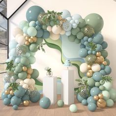 an arch made out of balloons and greenery is displayed in front of a wall