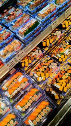 many trays of sushi are on display in the store's deli