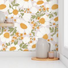 a white vase sitting on top of a counter next to a wallpapered wall