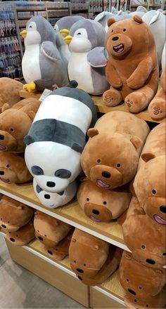 several stuffed animals are on display in a store with penguins and pandas behind them