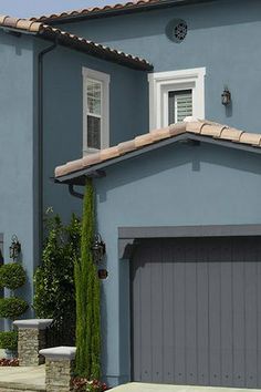 a blue house with two garage doors and windows