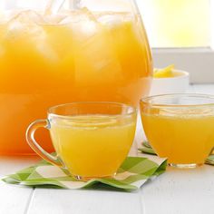 two glasses filled with orange juice next to a pitcher