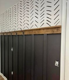 an empty hallway with black doors and white wallpaper on the walls, along with wooden flooring