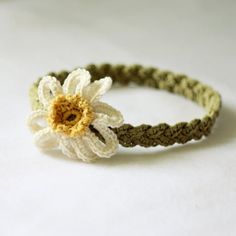 a crocheted bracelet with a white flower on the front and green cord around it