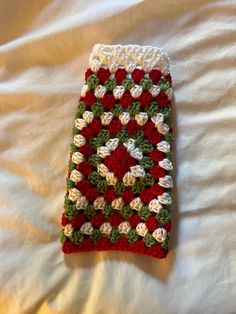 a crocheted red and white blanket laying on top of a bed