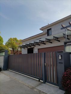 a house that has a metal fence in front of it and some bushes on the side