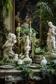 a table topped with white statues and greenery