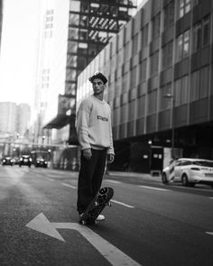 a man riding a skateboard down the middle of a street next to tall buildings