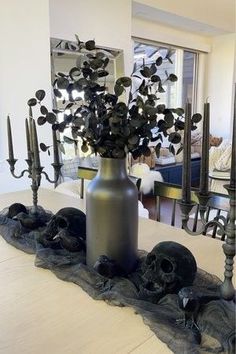 there is a vase with flowers in it on the table next to candles and skulls