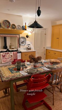 a kitchen with yellow cabinets and red chairs around a table that has plates on it