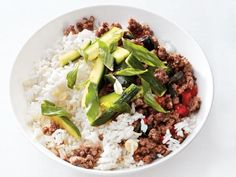 a white bowl filled with rice, meat and veggies on top of it