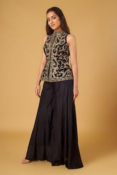 Black sleeveless jacket with all over gold zari anthemion bloom embroidery using sequin, beads highlights. Paired with a flared sharara pant. - Aza Fashions Sleeveless Nehru Jacket With Zari Work, Sleeveless Nehru Jacket With Resham Embroidery, Fitted Sleeveless Nehru Jacket With Intricate Embroidery, Fitted Bollywood Style Sleeveless Nehru Jacket, Fitted Sleeveless Bollywood Nehru Jacket, Fitted Sleeveless Nehru Jacket With Zari Work, Elegant Gold Sleeveless Sets, Elegant Sleeveless Nehru Jacket For Festive Occasion, Festive Resham Embroidered Sleeveless Vest