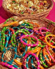 two baskets filled with lots of colorful bracelets on top of a table next to each other