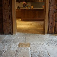 an open door leading into a kitchen with stone floors and wooden cabinets in the background