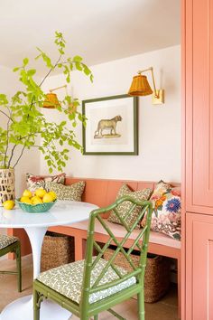 a dining room with pink walls, green chairs and a white table topped with fruit