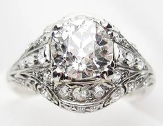 an antique style diamond ring with filigrees on the sides and center stone