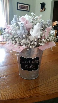 a metal bucket filled with baby's breath flowers and welcome baby written on the side