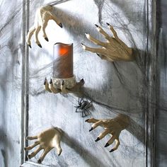 some fake hands are hanging on the wall next to a candle and spider webs