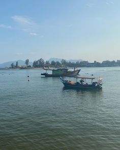 two boats floating on top of a large body of water next to a shore line