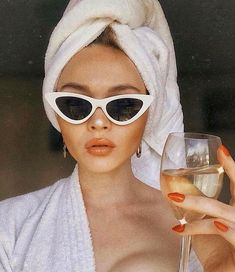 a woman wearing sunglasses and a towel holding a wine glass