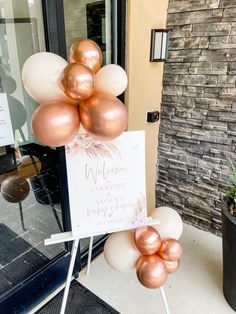 a welcome sign and some balloons in front of a door with a brick wall behind it