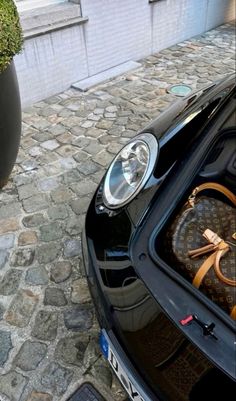 a black car parked on the side of a road next to a planter filled with flowers