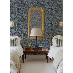 two beds in a room with blue wallpaper and a large mirror on the wall