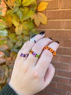 a woman's hand with two rings on it and some leaves in the background