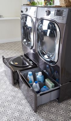 a washer and dryer sitting next to each other in a room with tile flooring