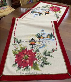 a christmas table runner with poinsettis and holly on it is sitting on the floor