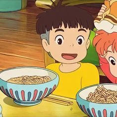 two children sitting at a table with bowls of food