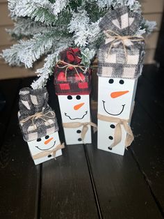 two snowmen are wrapped in burlocks and tied with twine, sitting next to a christmas tree