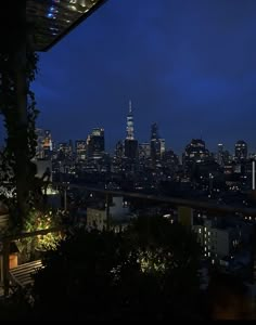 the city skyline is lit up at night, as seen from an outdoor patio area