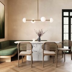 a dining room table with four chairs and a vase on the table in front of it