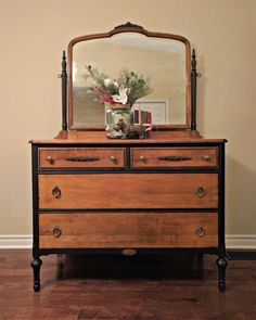 an old dresser with a mirror and flowers on top