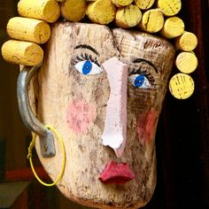 a wooden mask with blue eyes and blonde hair is hanging from a hook on a wall