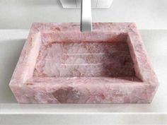 a pink marble sink sitting on top of a white counter