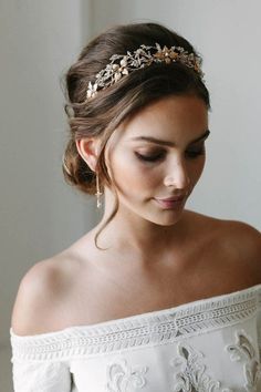 a woman wearing a white dress and a gold headpiece with flowers on it's hair