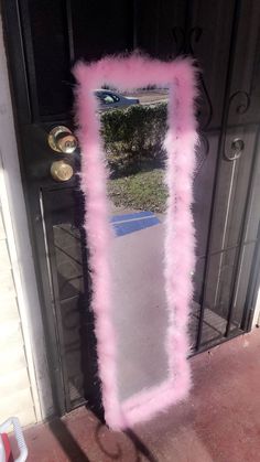 a pink mirror sitting on the side of a door with some fake fur around it