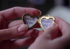 someone holding two small hearts with writing on them